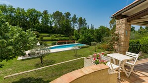 Una piscina circondata da un giardino rigoglioso con un patio che include un tavolo e panche.