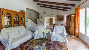 Un salon spacieux avec un plafond haut, un escalier, une bibliothèque en bois et un coin repas.