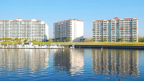 Ein Hotel am Wasser mit mehreren Hochhäusern, einer Marina voller Boote und einem klaren, blauen Himmel.