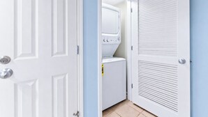 Un cuarto de lavado con lavadora y secadora, una puerta con cerradura y una pared con ventana.