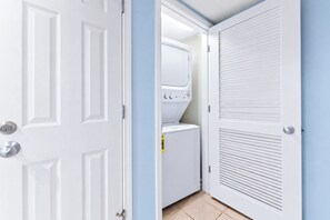 Een wasserette met een wasmachine en droger, een deur met een sleutel slot, en een muur met een raam.