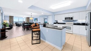 Una cocina moderna con armarios blancos, una isla central y un comedor con sillas y una mesa.