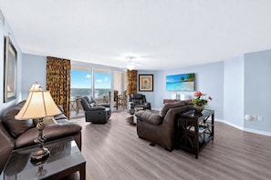 A modern living room with a sofa, two recliners, a coffee table, and a TV.
