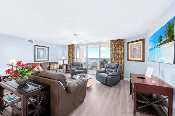 A modern living room with a sofa, armchairs, a coffee table, and a TV. - Large Elegant Condo with Waterway View, Onsite Day Spa | Yacht Club Villas - 1-1004 (North Myrtle Beach)