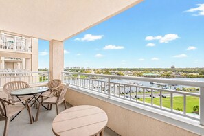 A balcony with a table and chairs, overlooking a marina with boats and a river.