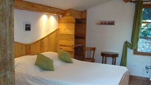 Une chambre à coucher avec une tête de lit en bois, un lit avec des oreillers verts, une petite table et une chaise.