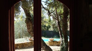 Un portail en arc donnant sur un jardin agrémenté d’une piscine et d’arbres.