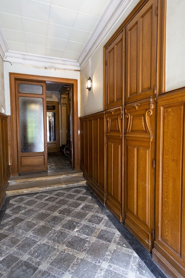 Un couloir aux murs lambrissés, doté d’un sol carrelé et d’une porte en verre dépoli.