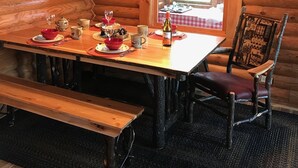 En stuga med träpanel på insidan, med ett matbord för fyra personer, en bänk och en stol.