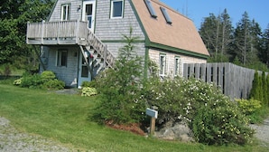 A two-story house with a wooden deck and a front porch.