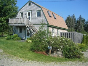 A two-story house with a wooden deck and a front porch.