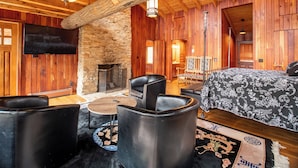 A rustic interior with a stone fireplace, leather furniture, and wooden walls.