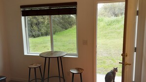 Ein Zimmer mit großem Fenster, einer Tür und zwei Barhocker.