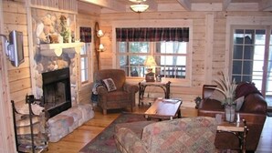 Interior acogedor de una cabaña con chimenea, paredes de madera, un sofá cómodo y una mesa de comedor.
