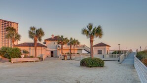 A coastal hotel with a sandy beach, palm trees, and a wooden boardwalk. - Oceanfront condo in private community + Free Attraction Tickets! (Myrtle Beach)