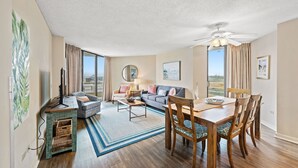 A spacious living area with a sofa, chairs, a dining table, and a ceiling fan. - Oceanfront condo in private community + Free Attraction Tickets! (Myrtle Beach)