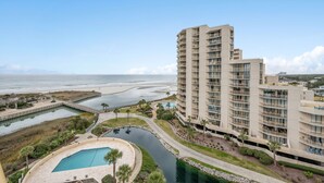 A high-rise hotel with multiple balconies, a swimming pool, and a view of the beach and ocean. - Oceanfront condo in private community + Free Attraction Tickets! (Myrtle Beach)
