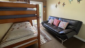 Quarto com uma cama beliche, um sofá de couro preto e arte de parede decorativa com peixes.