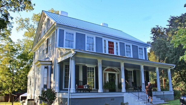 A two-story house with a porch, large windows, and a covered front entrance.
