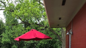 A wooden deck with outdoor furniture, including a table and chairs, and a red umbrella.