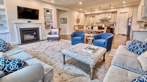 A living room with a fireplace, two blue armchairs, a sofa, and a coffee table. - Coastal Club * Ultimate Game Room w/ Resort-Style Amenities (Lewes)