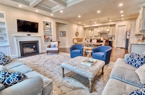 A living room with a fireplace, two blue armchairs, a sofa, and a coffee table.