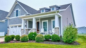 A two-story house with a covered porch, a garage, and a well-maintained lawn. - Coastal Club * Ultimate Game Room w/ Resort-Style Amenities (Lewes)