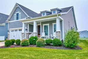 A two-story house with a covered porch, a garage, and a well-maintained lawn.