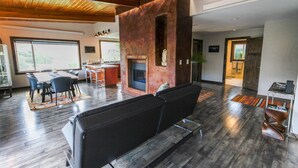 A modern living room with a fireplace, seating area, and a dining space.