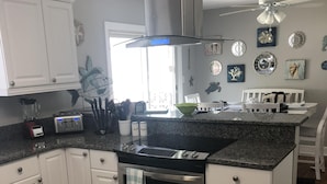 A modern kitchen with white cabinetry, a stainless steel oven, and a granite countertop. - Fully Fenced in Backyard, 1 block to the beach, Golf Cart included, (Myrtle Beach)