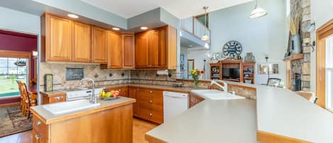 A spacious kitchen with wooden cabinets, a large island, and a stone accent wall.