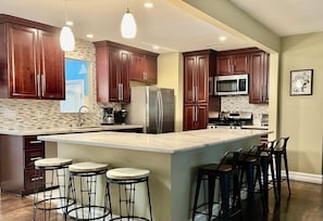 Una cocina moderna con armarios de madera oscura, electrodomésticos de acero inoxidable y una isla grande con taburetes de bar.