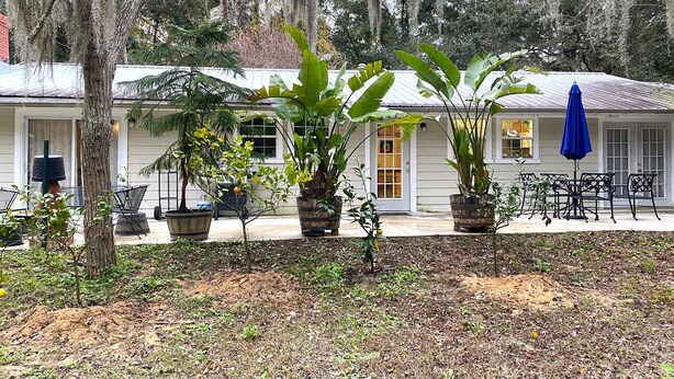Ett hus med en veranda, krukväxter och utemöbler.