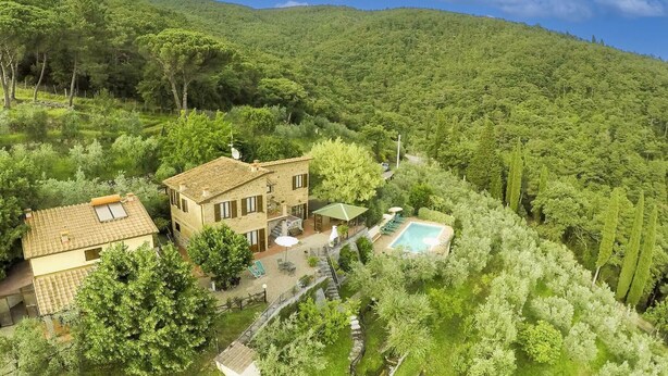 Ein Haus mit Pool, umgeben von üppiger Vegetation und Hügeln.