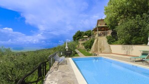 Ein Pool mit einer Steindeck, einer Steinmauer und Blick auf die Landschaft.