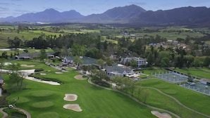 Campo de golf con un club de campo, rodeado de montañas y zonas residenciales.