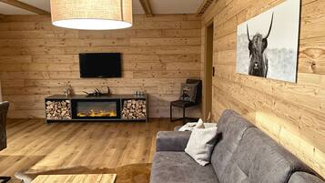 A wooden interior with a sofa, a fireplace, a TV, and a mounted picture.