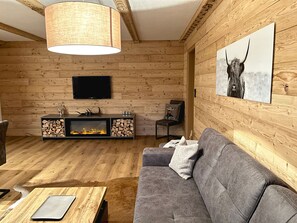 Interior de madera con un sofá, una chimenea, un televisor y un cuadro colgado.