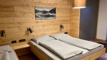A wooden-paneled bedroom with a bed, bedside lamps, and a wall-mounted picture.