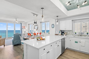 A spacious kitchen with a large island, white cabinetry, and a view of the ocean.