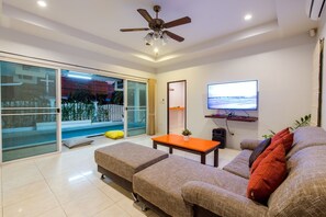 A modern living room with a sofa, ottoman, and a television.