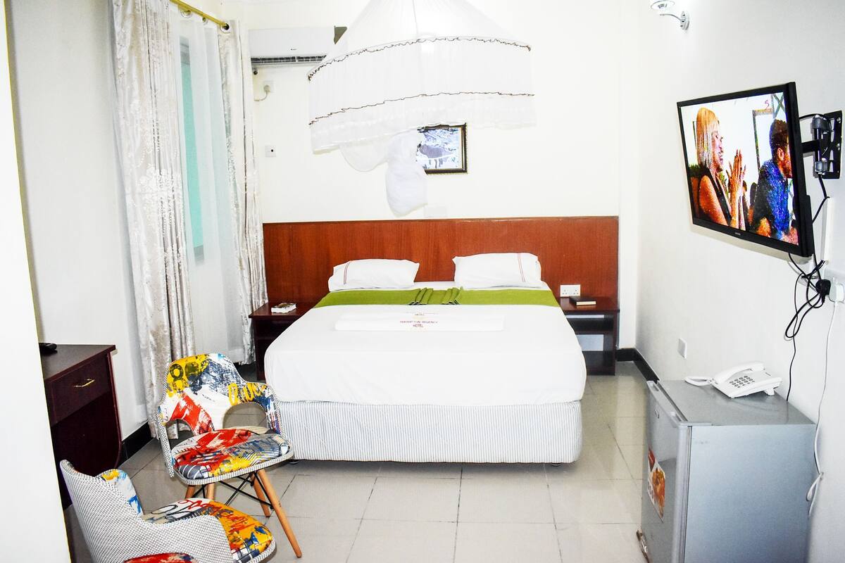A hotel room with a bed, a television, a desk, and a chair.