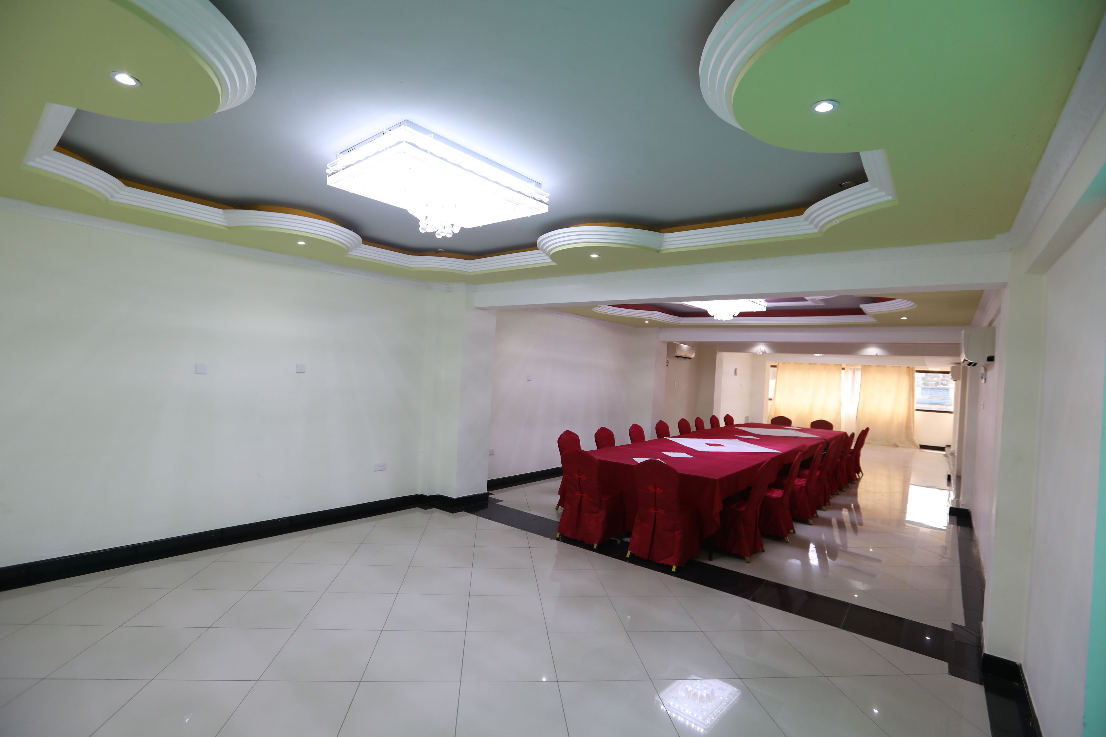 A conference room with a long table and chairs, a chandelier, and a tiled floor.