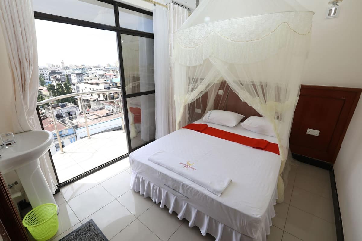 A hotel room with a bed, a window, a sink, and a balcony.