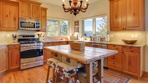 A spacious kitchen with wooden cabinets, stainless steel appliances, a large island, and a chandelier. - Lake & Mountain Views: Stunning Estes Park Home! (Estes Park)