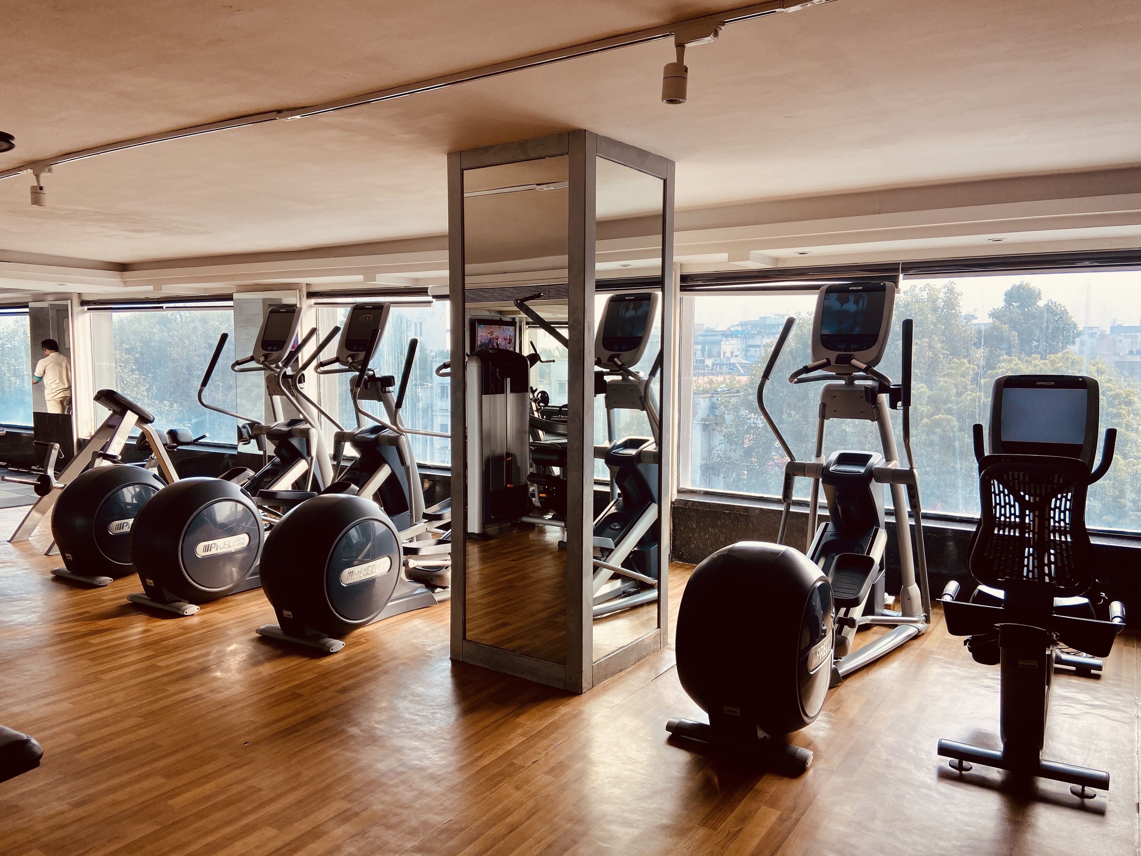 A gym with cardio machines, weight equipment, and a large mirror.