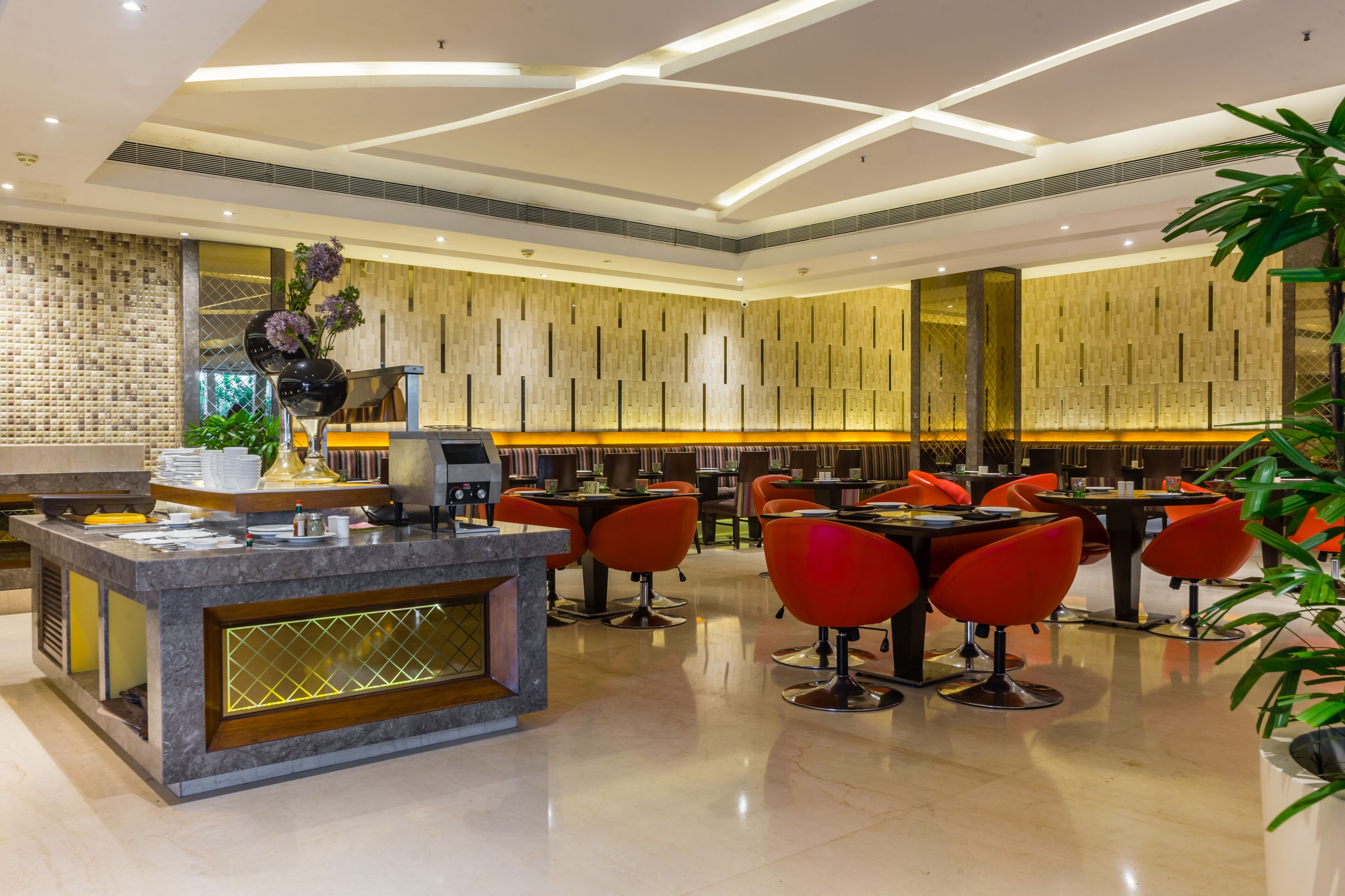 A modern hotel lobby with a reception desk, seating area, and decorative plants.