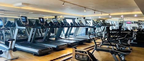 A gym with multiple treadmills, exercise bikes, and weight machines.