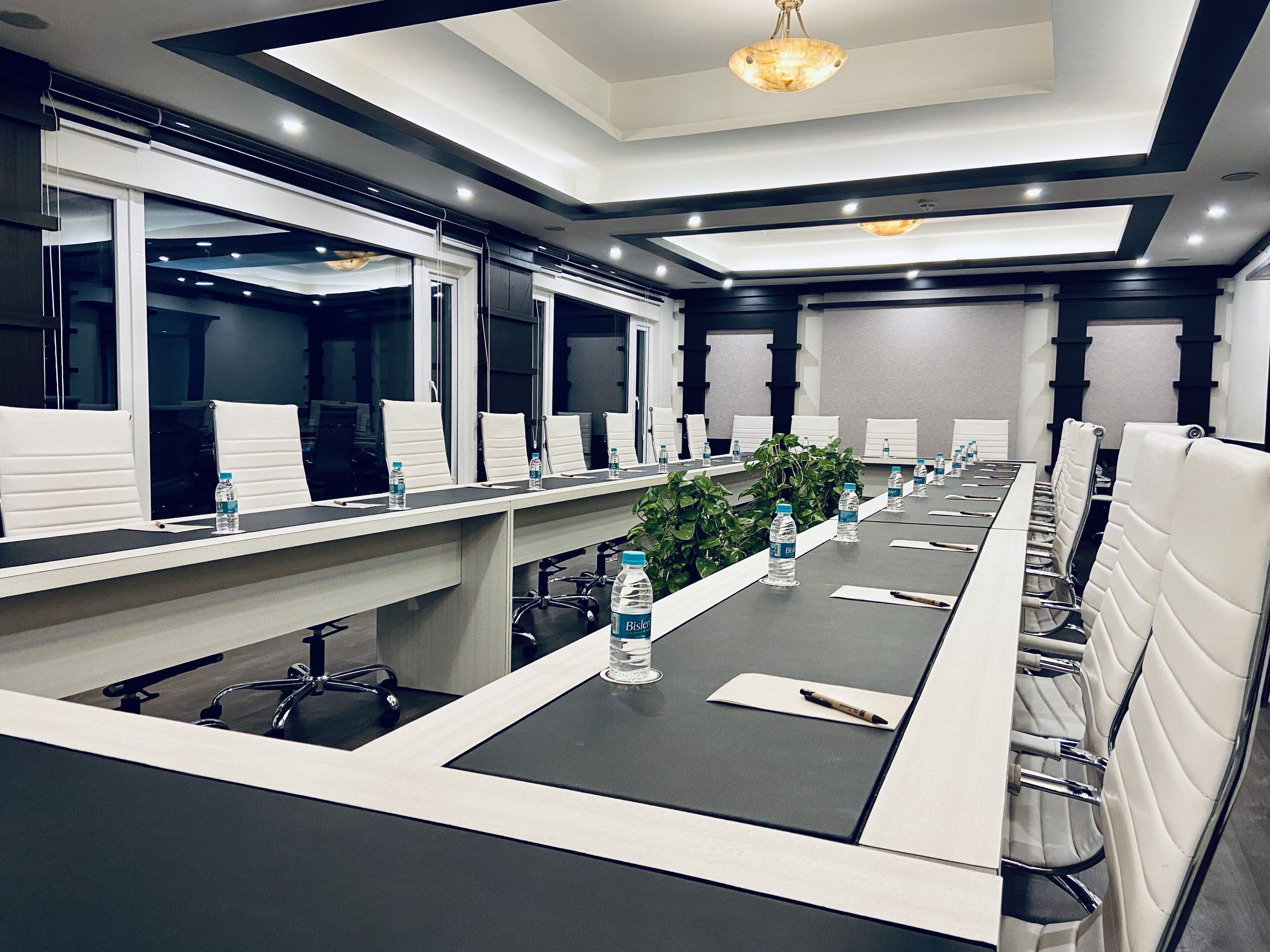 A conference room with a long table, white chairs, and water bottles.