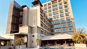 A hotel with a swimming pool, a modern building with multiple floors, and a palm tree. - The Landmark Hotel (Kanpur)